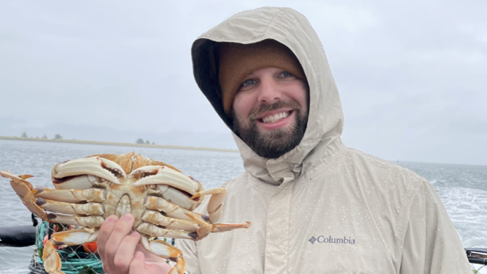 An image of Zack holding a crab on while on a boat, fishing